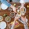 hands holding drinks over a table with food
